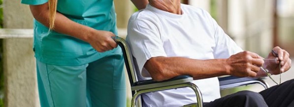 Krankenschwester redet mit Mann im Rollstuhl