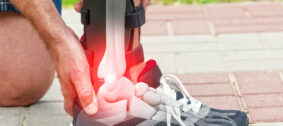 Man in athletic sneakers checking his ankle orthosis or brace on the street