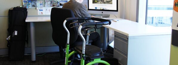 162older-woman-mobility-device-sitting-office-desk